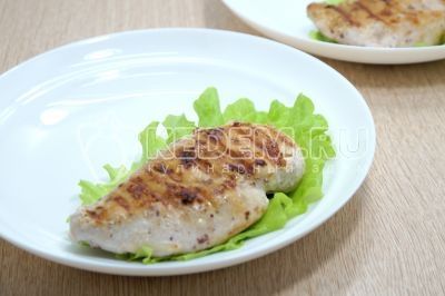 На тарелки выложить листья салата и выложить куриное филе.