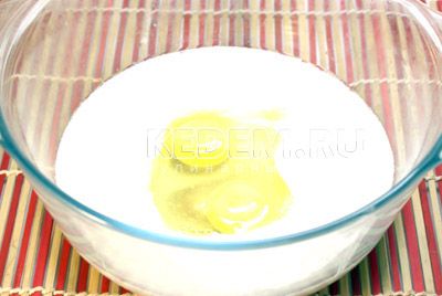 Отдельно, в большой миске, смешайте кефир, яйца (оставьте 1 желток), масло