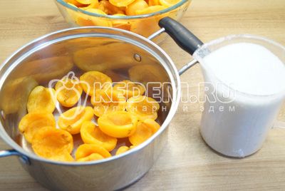 В кастрюлю выложить слой абрикосов и присыпать небольшим количеством сахара. Оставить 150 г сахара.